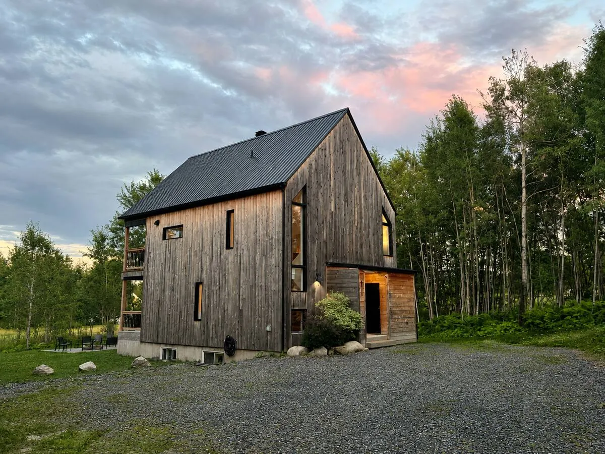 La Villa Foresta, en bois sombre, sous un ciel rose au crépuscule